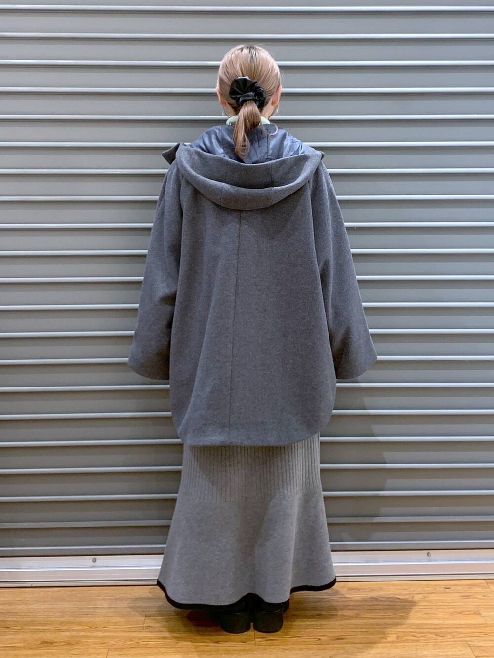 ホワイト系のショルダーバッグ、グレー系のポンチョ、ブラック系のブーツを着用したレディースの冬コーディネートの2枚目の写真