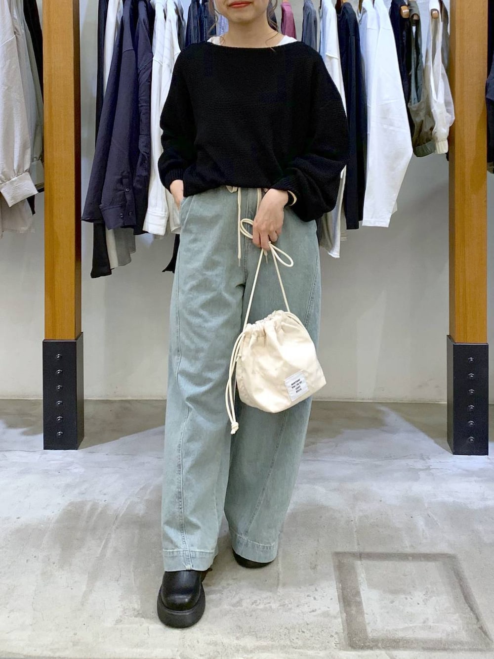 ブラック系のニット/セーター、ホワイト系のショルダーバッグ、ブルー系のデニムパンツを着用したレディースの春コーディネートの3枚目の写真