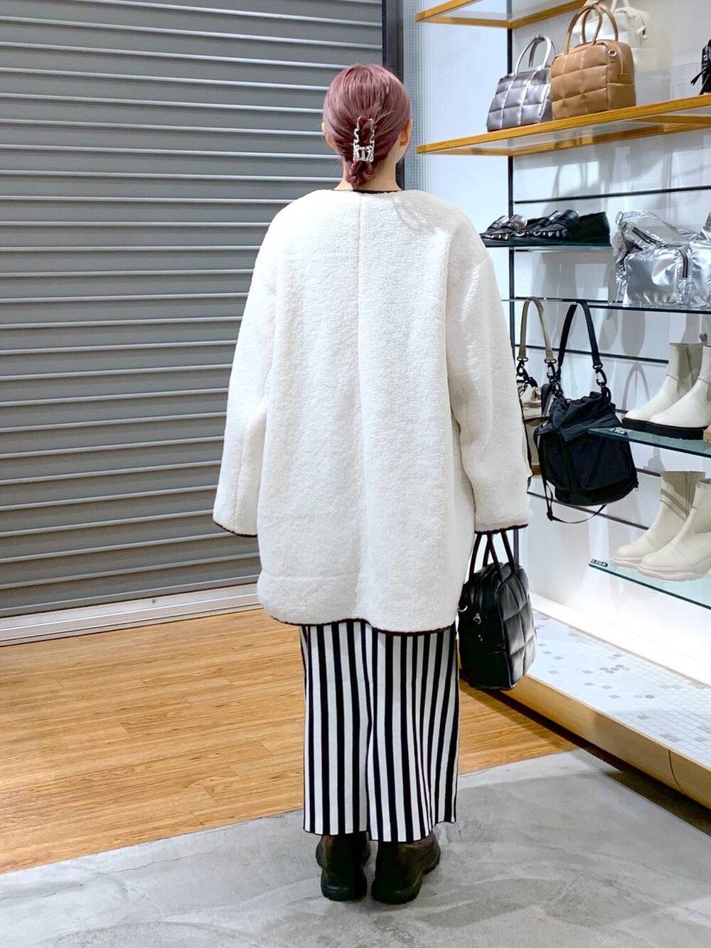 ブラック系のスカート、ホワイト系のその他アウター、ブラック系のボストンバッグを着用したレディースの秋コーディネートの2枚目の写真