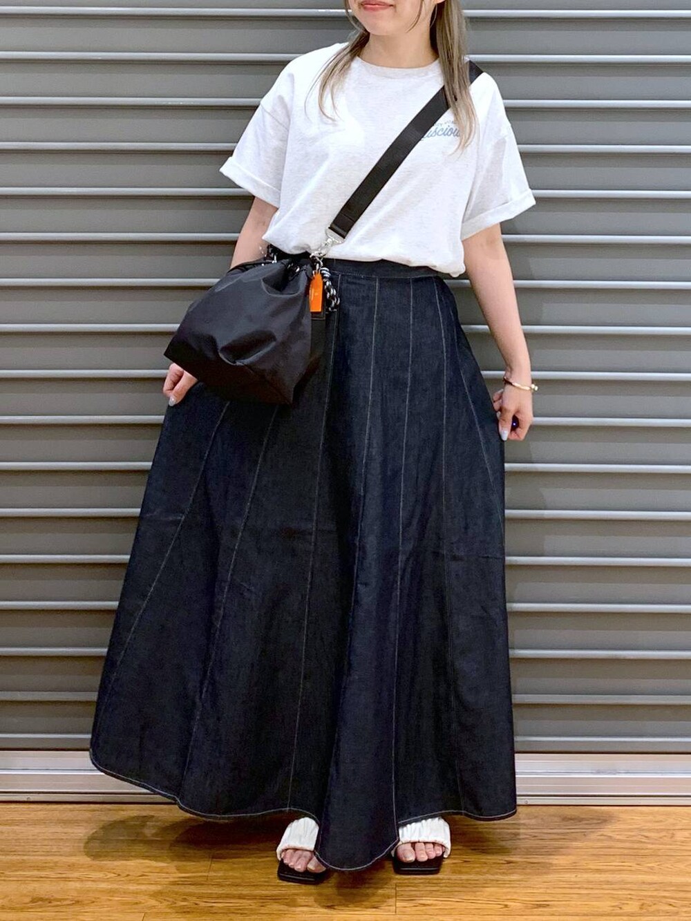 ブルー系のスカート、ホワイト系のサンダル、ブラック系のショルダーバッグを着用したレディースの夏コーディネートの5枚目の写真