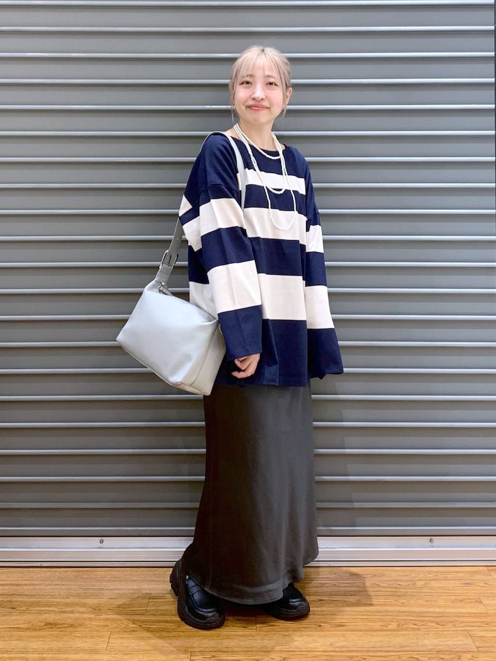 グレー系のスカート、グレー系のショルダーバッグ、ブラック系のスニーカーを着用したレディースの秋コーディネートの7枚目の写真