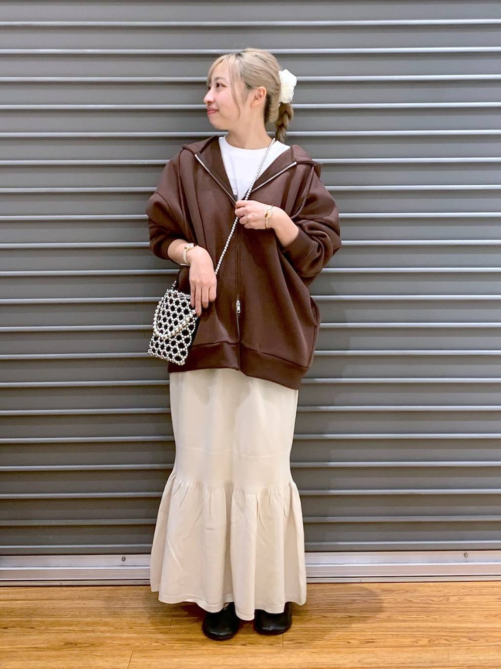 シルバー系のショルダーバッグ、ホワイト系のスカート、ブラウン系のパーカーを着用したレディースの秋コーディネートの6枚目の写真