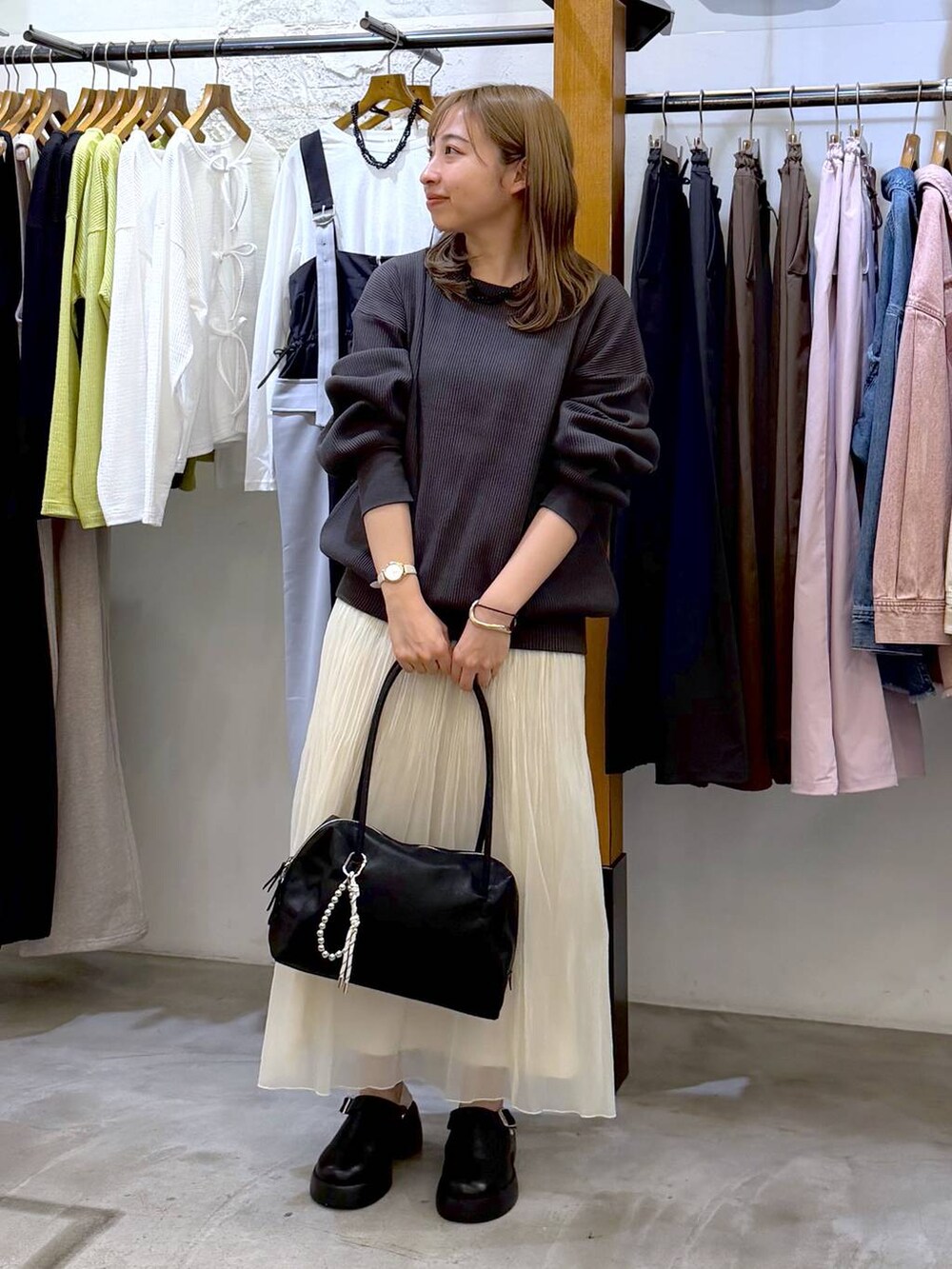 ブラック系のサンダル、ブラック系のボストンバッグ、ホワイト系のスカートを着用したレディースの春コーディネートの5枚目の写真