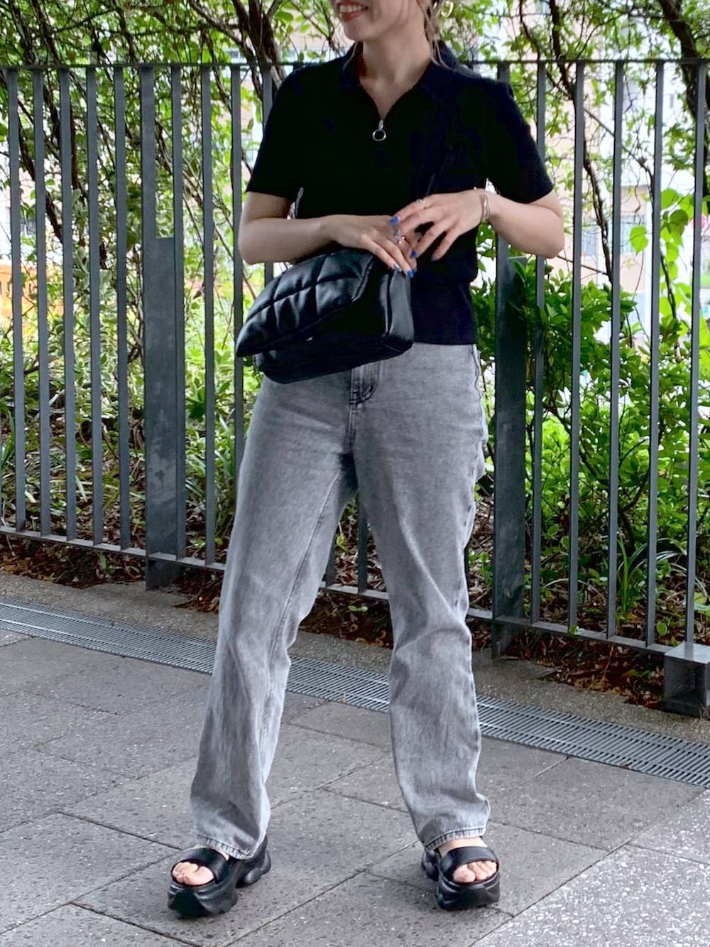 ブラック系のショルダーバッグ、ブラック系のサンダル、グレー系のデニムパンツを着用したレディースの夏コーディネートの4枚目の写真