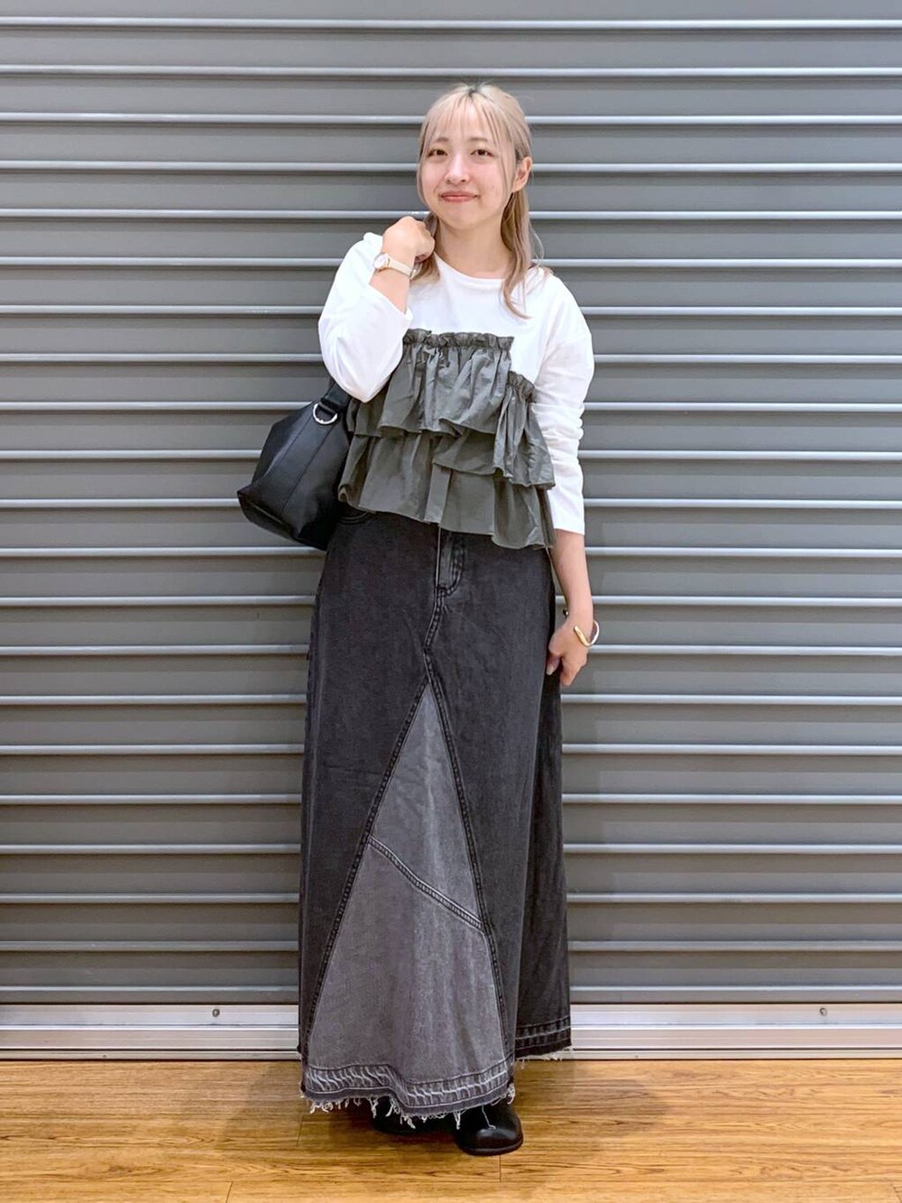 ブラック系のデニムスカート、グリーン系のTシャツ/カットソー、ブラック系のショルダーバッグを着用したレディースの秋コーディネートの5枚目の写真