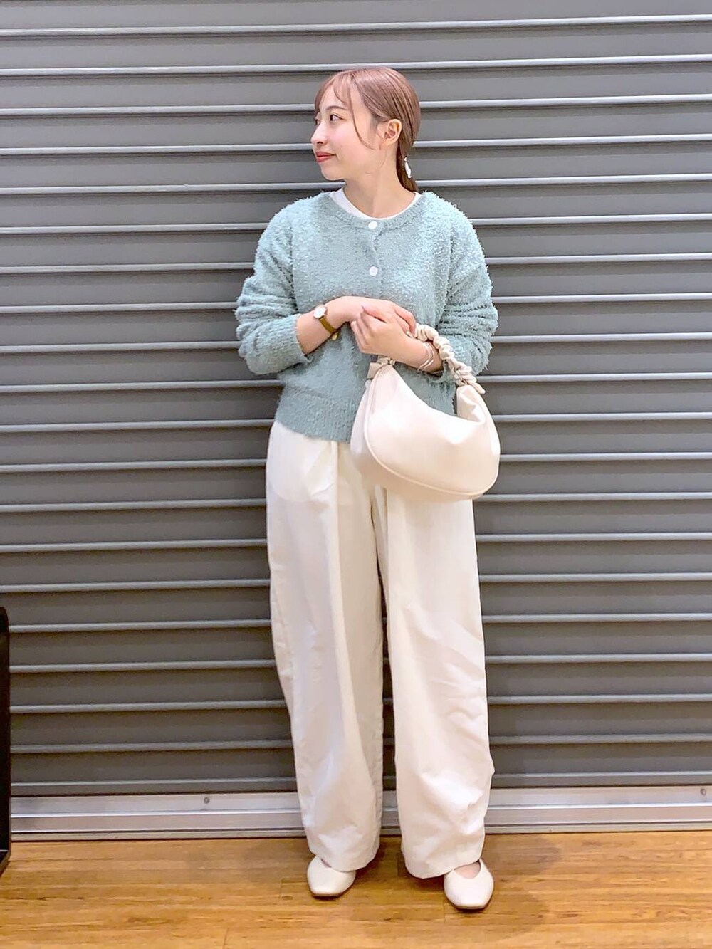 ホワイト系のショルダーバッグ、ホワイト系のパンプス、グリーン系のカーディガン/ボレロを着用したレディースの春コーディネートの4枚目の写真