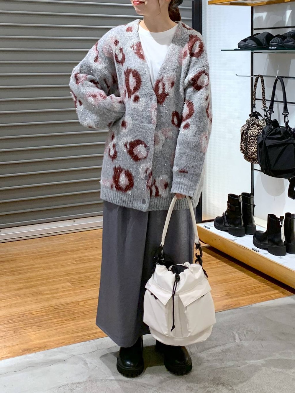 ホワイト系のショルダーバッグ、ブラック系のブーツ、ブラック系のスカートを着用したレディースの冬コーディネートの6枚目の写真