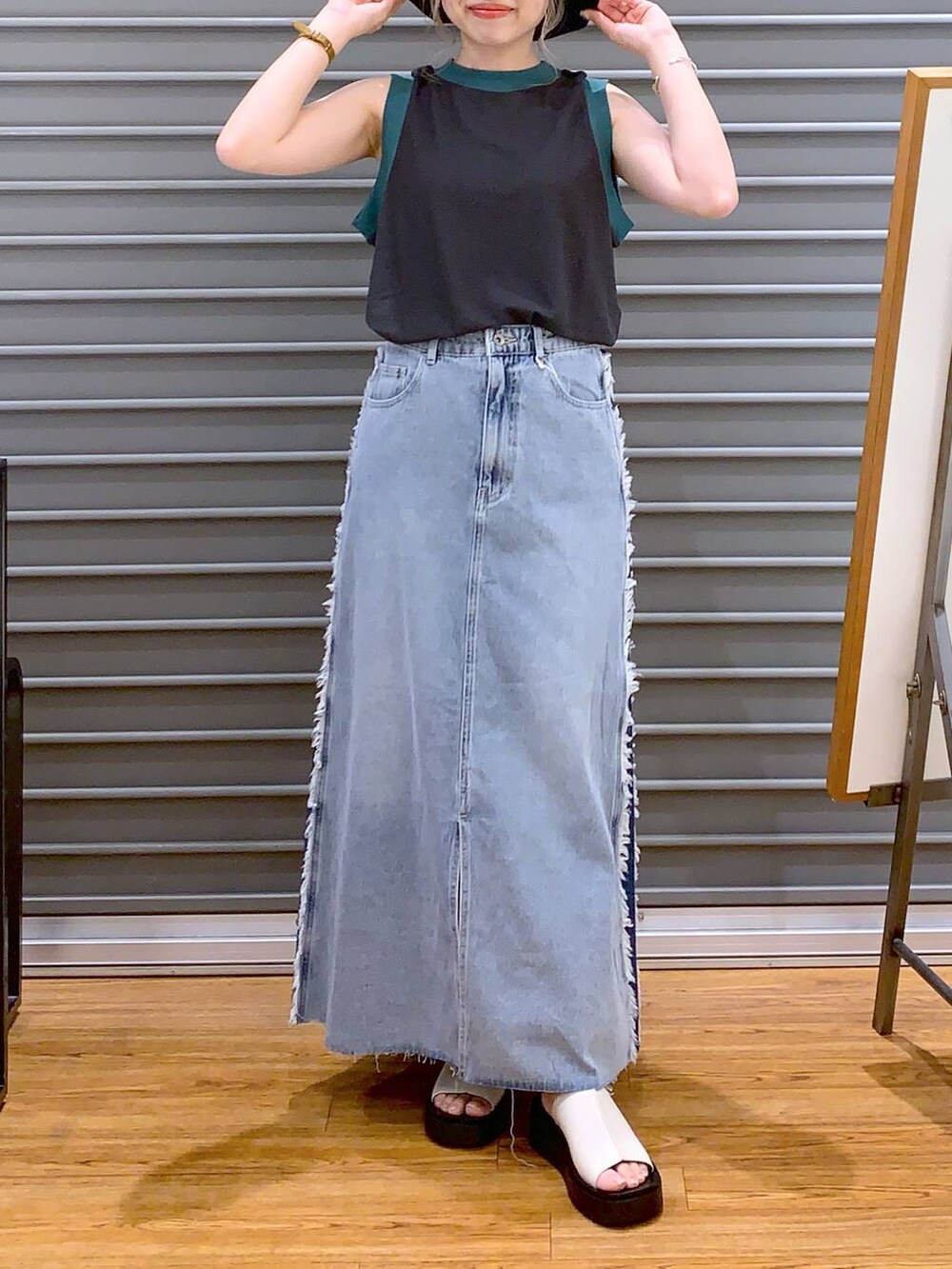 グレー系のタンクトップ、ホワイト系のサンダル、ブラック系のショルダーバッグを着用したレディースの夏コーディネートの2枚目の写真