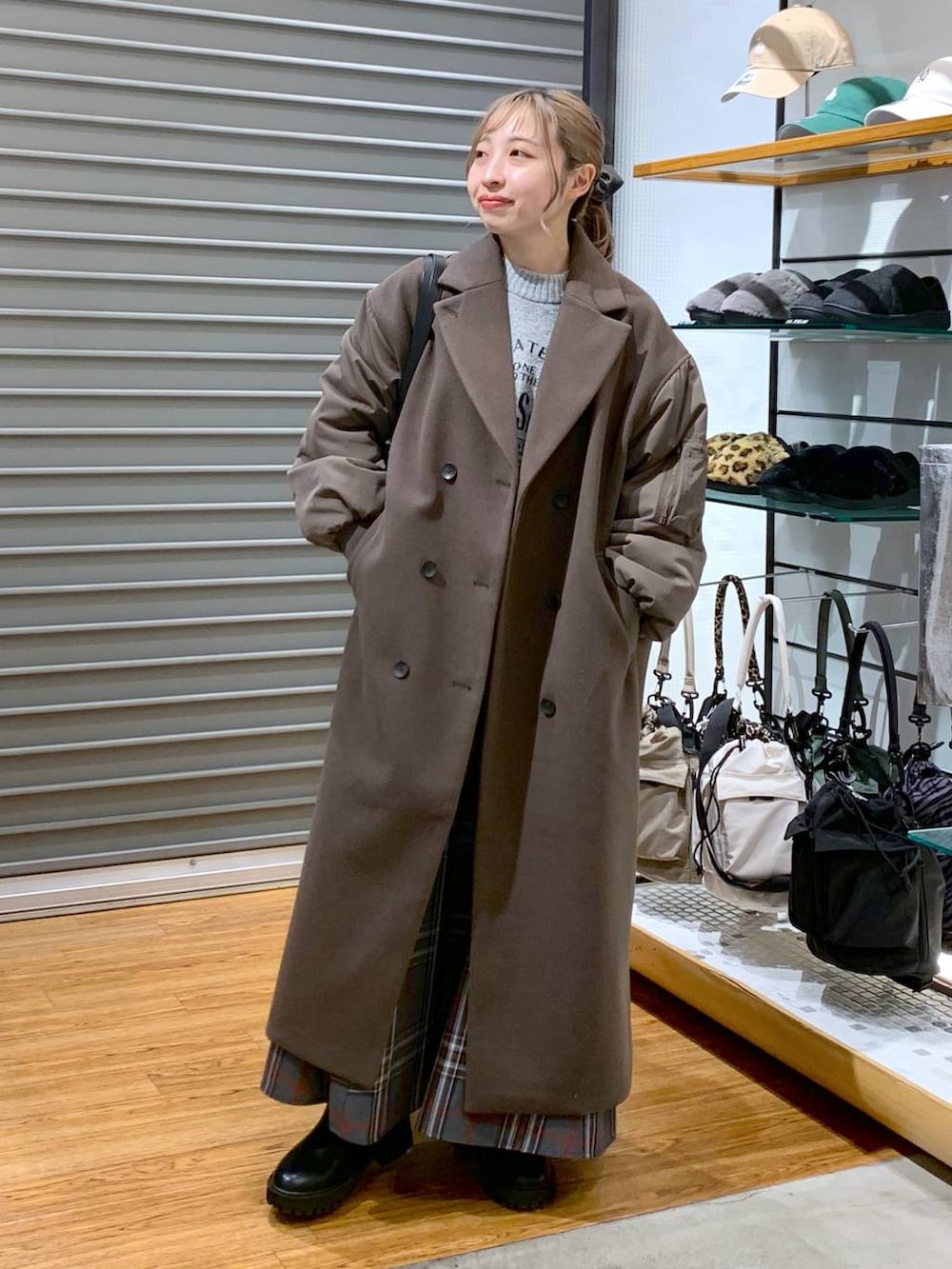 ブラック系のブーツ、グレー系のスカート、ブラック系のショルダーバッグを着用したレディースの冬コーディネートの3枚目の写真