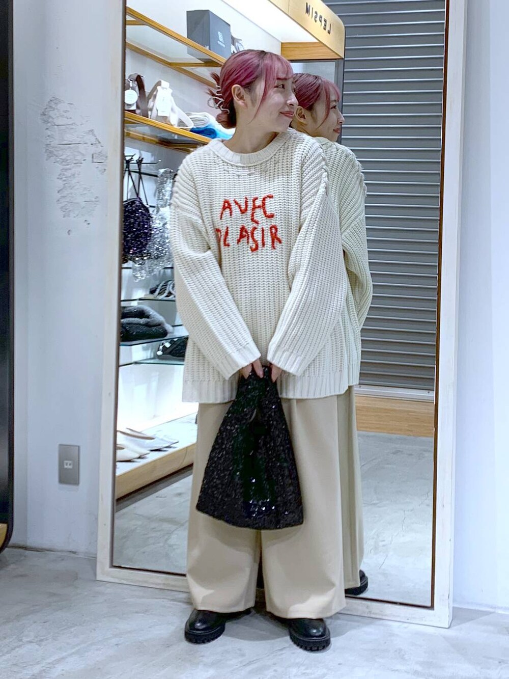 ブラック系のブーツ、ホワイト系のニット/セーター、ブラック系のハンドバッグを着用したレディースの秋コーディネートの3枚目の写真