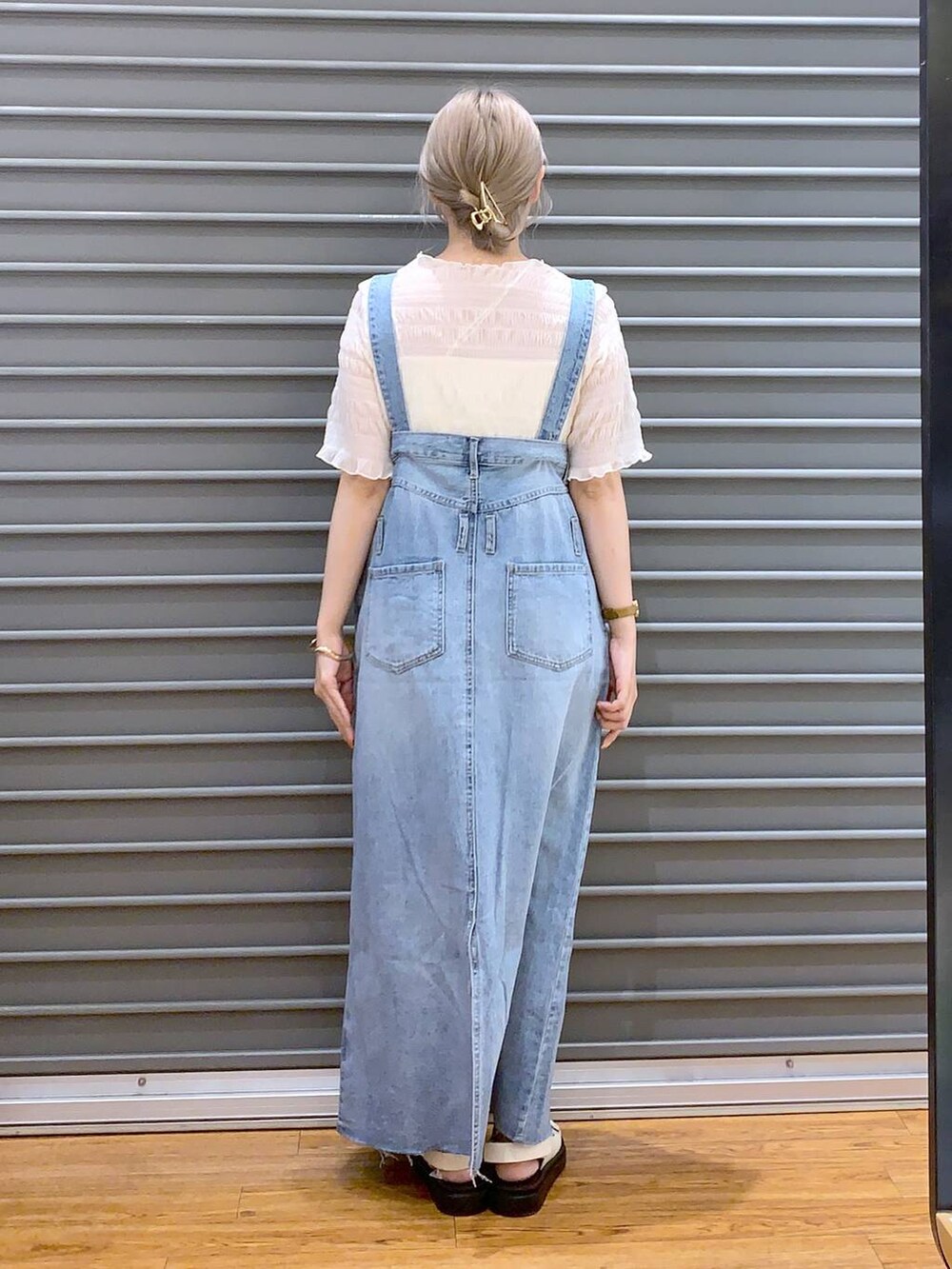 ホワイト系のショルダーバッグ、ホワイト系のキャミソール、ブルー系のジャンパースカートを着用したレディースの春コーディネートの2枚目の写真