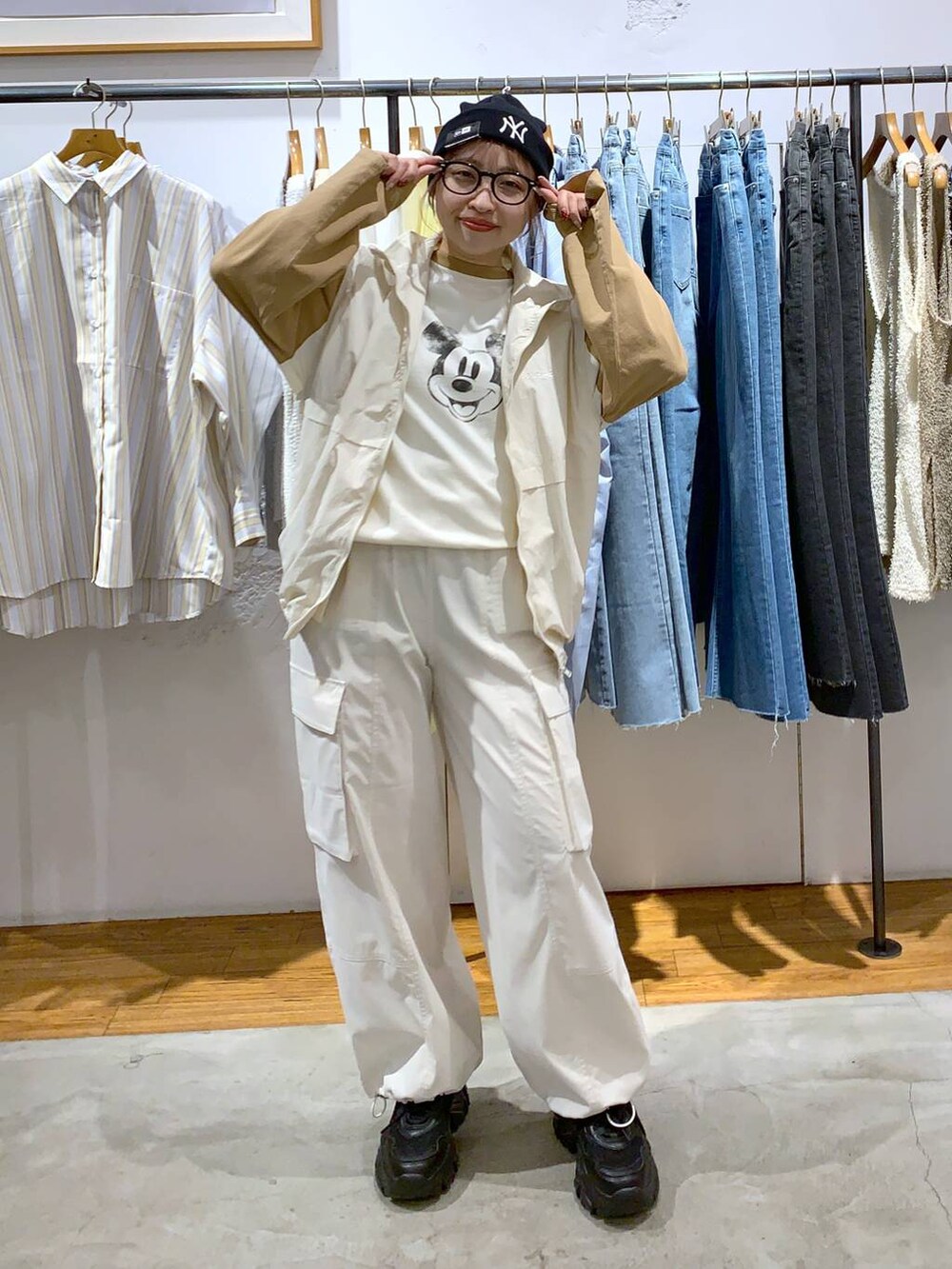 ブラック系のスニーカー、イエロー系のショルダーバッグ、ホワイト系のベストを着用したレディースの春コーディネートの3枚目の写真