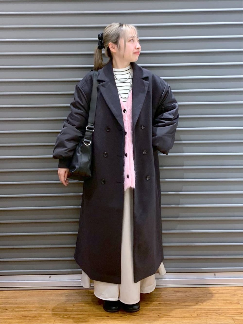 ブラック系のショルダーバッグ、ホワイト系のニット/セーター、ブラック系のブーツを着用したレディースの冬コーディネートの7枚目の写真