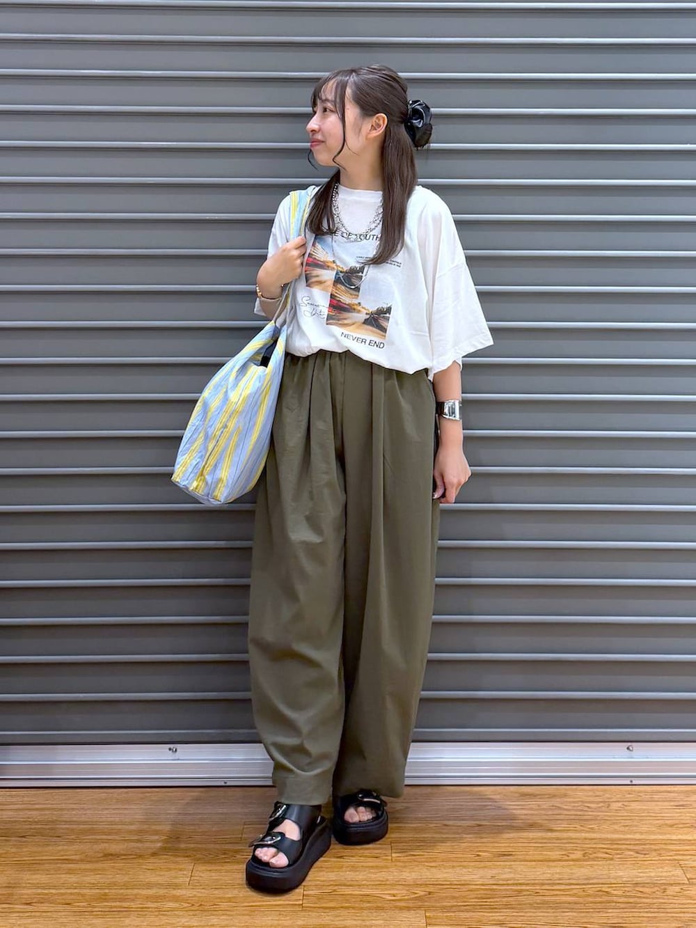 ブルー系のトートバッグ、ホワイト系のTシャツ/カットソー、ブラック系のサンダルを着用したレディースの夏コーディネートの5枚目の写真