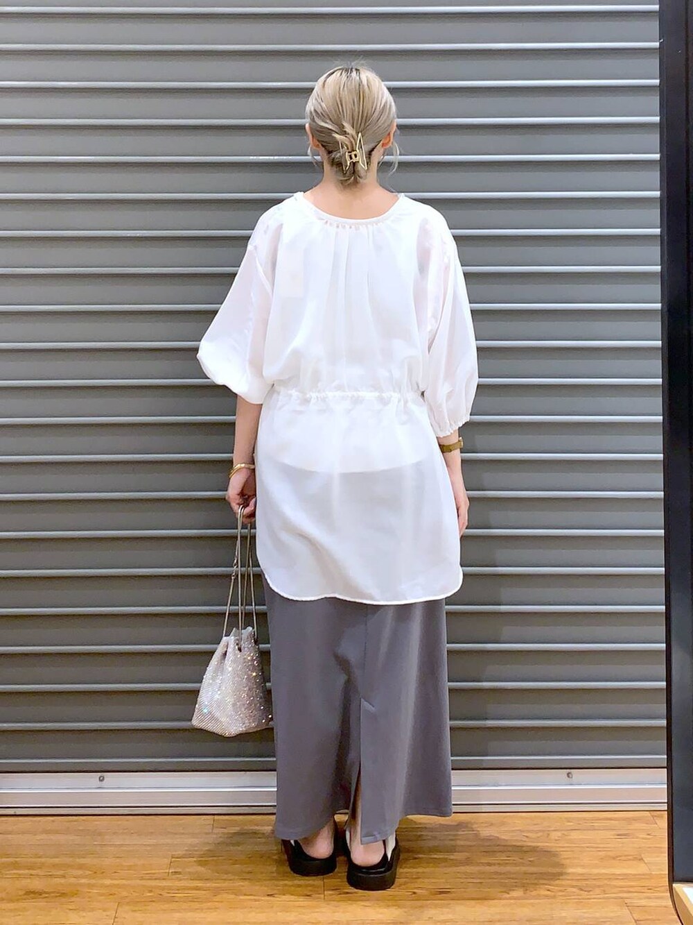 ホワイト系のショルダーバッグ、グレー系のスカート、ホワイト系のサンダルを着用したレディースの夏コーディネートの2枚目の写真