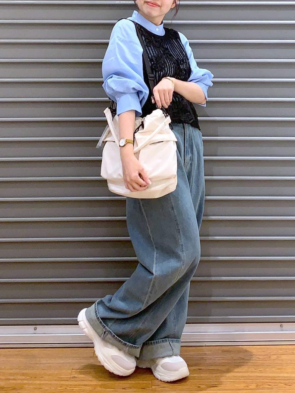 ホワイト系のショルダーバッグ、ブルー系のデニムパンツ、ホワイト系のスニーカーを着用したレディースの秋コーディネートの4枚目の写真
