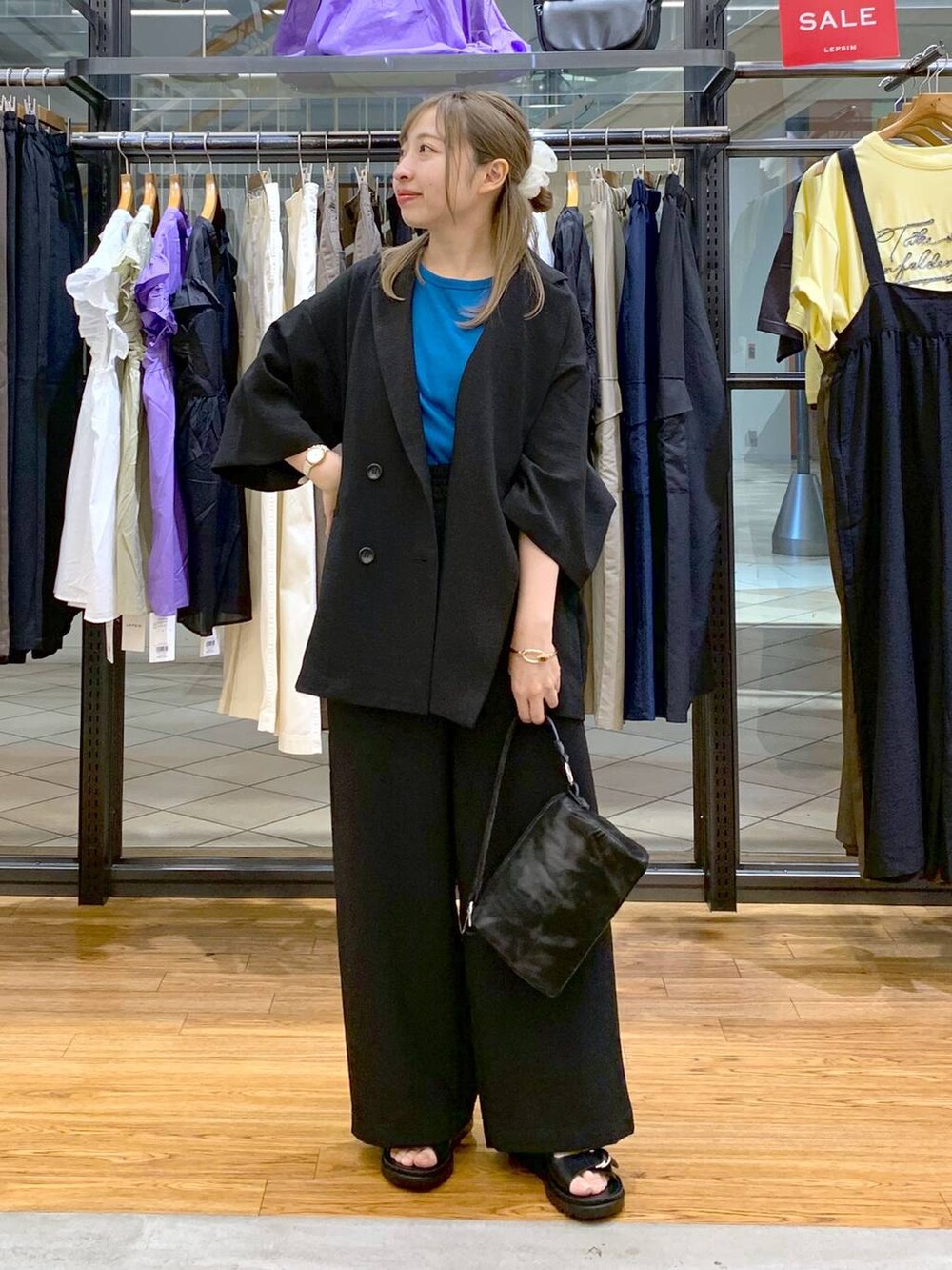 ブラック系のテーラードジャケット、ブルー系のタンクトップ、ブラック系のサンダルを着用したレディースの夏コーディネートの4枚目の写真