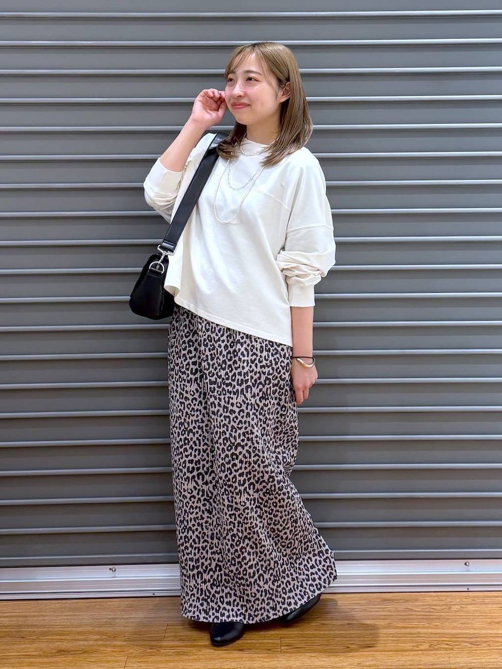 ブラック系のショルダーバッグ、ホワイト系のTシャツ/カットソー、ブラック系のパンプスを着用したレディースの春コーディネートの4枚目の写真