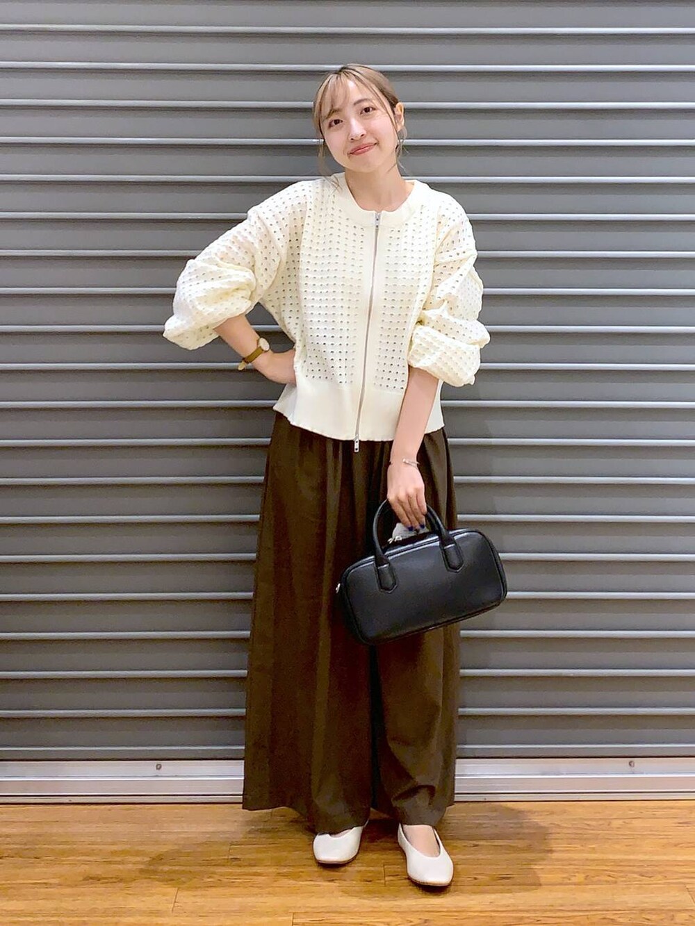 ブラウン系のスラックス、ホワイト系のパンプス、ブラック系のボストンバッグを着用したレディースの秋コーディネートの3枚目の写真