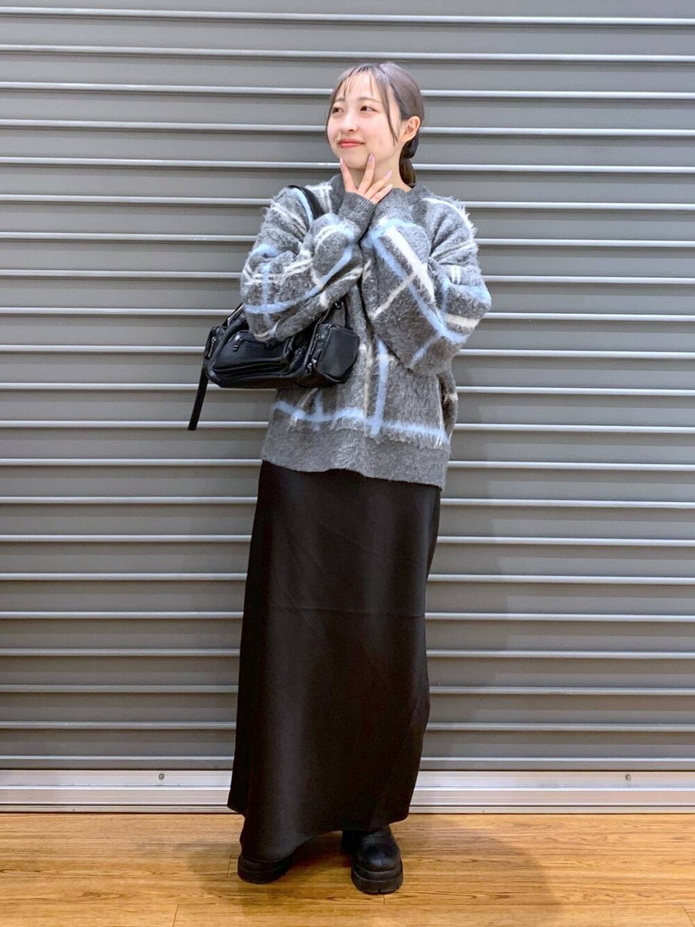 ブラック系のスカート、ブラック系のブーツ、ブラック系のショルダーバッグを着用したレディースの冬コーディネートの3枚目の写真