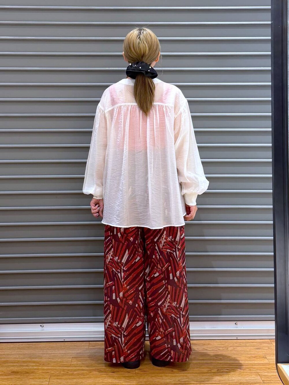 レッド系のその他パンツ、ホワイト系のサンダル、ベージュ系のシャツ/ブラウスを着用したレディースの夏コーディネートの2枚目の写真