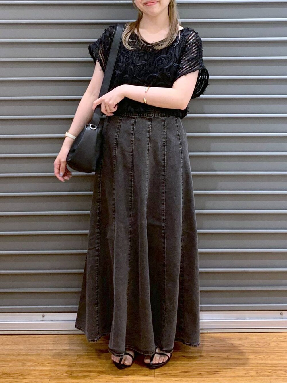 ブラック系のショルダーバッグ、グレー系のスカート、ブラック系のサンダルを着用したレディースの夏コーディネートの6枚目の写真