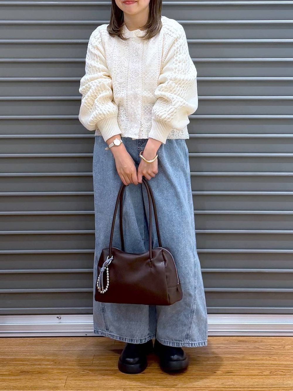 ブラック系のサンダル、ブルー系のデニムパンツ、ブラウン系のボストンバッグを着用したレディースの春コーディネートの6枚目の写真