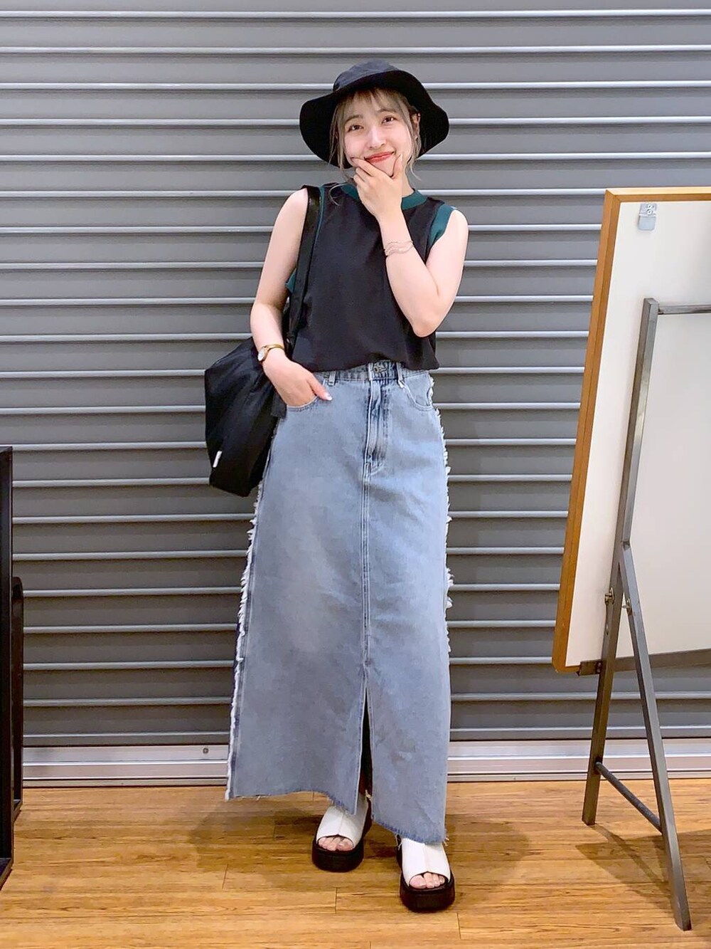 グレー系のタンクトップ、ホワイト系のサンダル、ブラック系のショルダーバッグを着用したレディースの夏コーディネートの3枚目の写真
