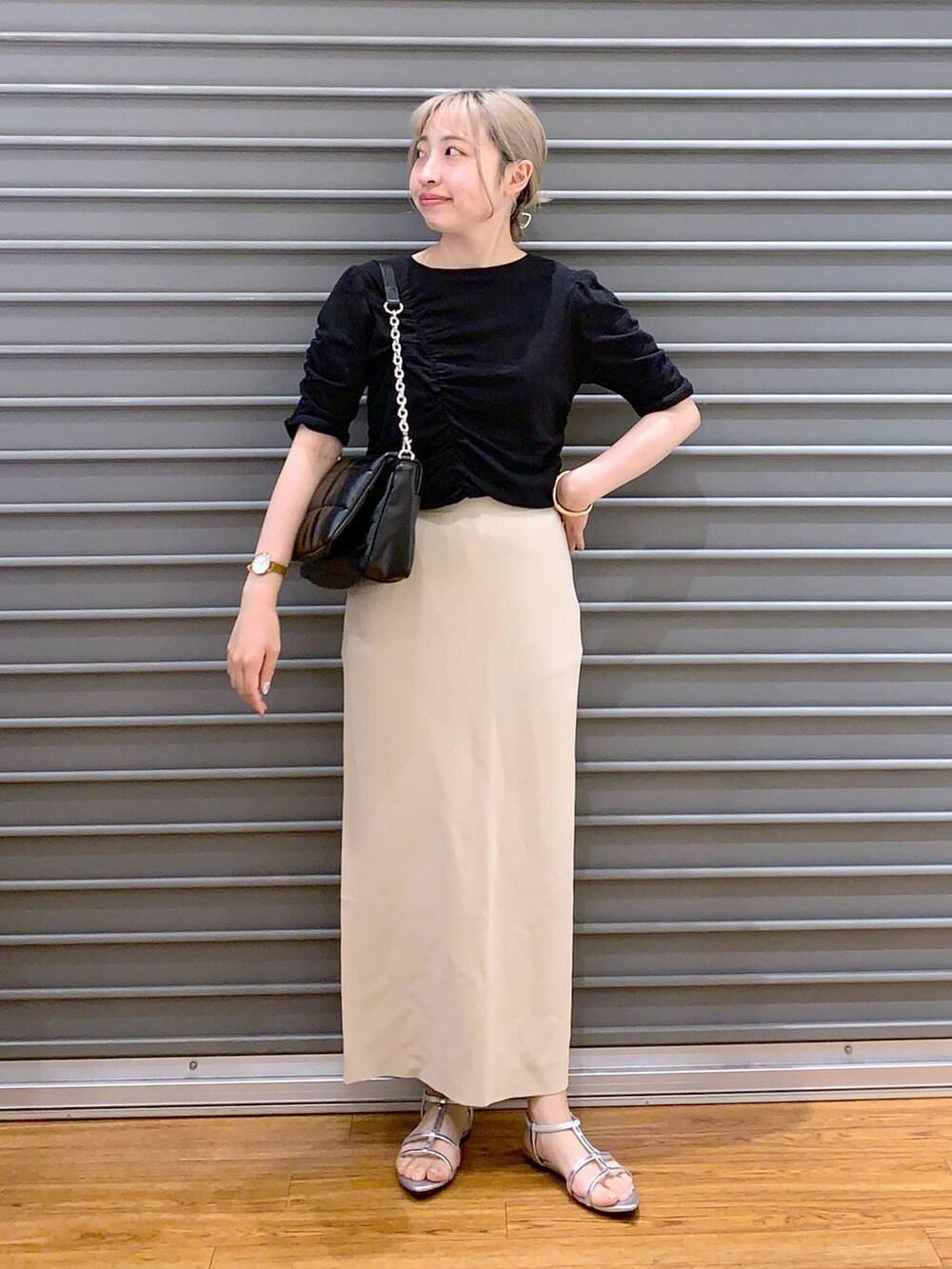 ブラック系のショルダーバッグ、ベージュ系のスカート、シルバー系のサンダルを着用したレディースの春コーディネートの3枚目の写真