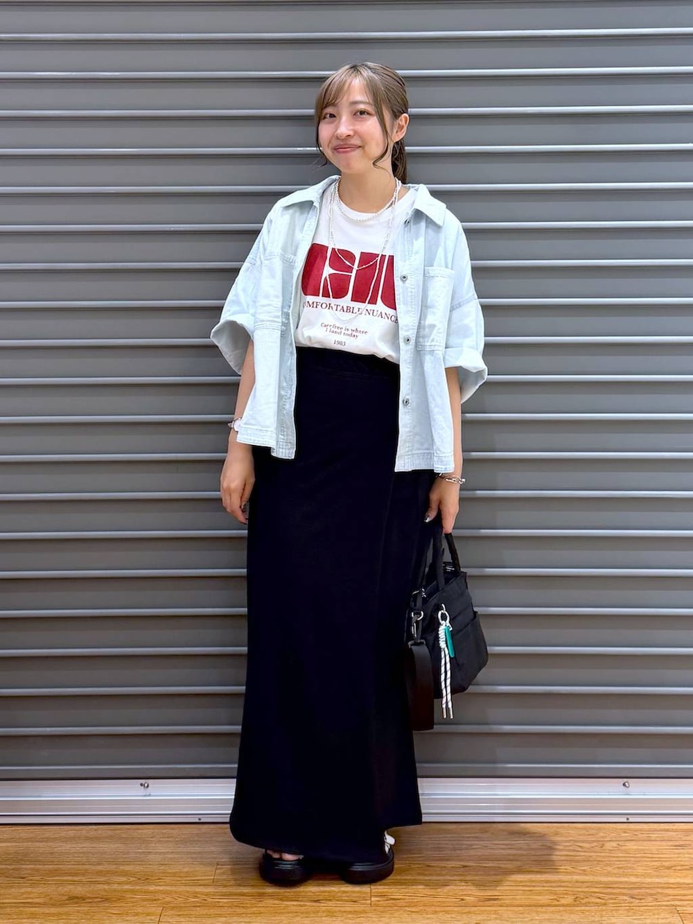 ブラック系のスカート、ホワイト系のTシャツ/カットソー、ブラック系のトートバッグを着用したレディースの夏コーディネートの4枚目の写真