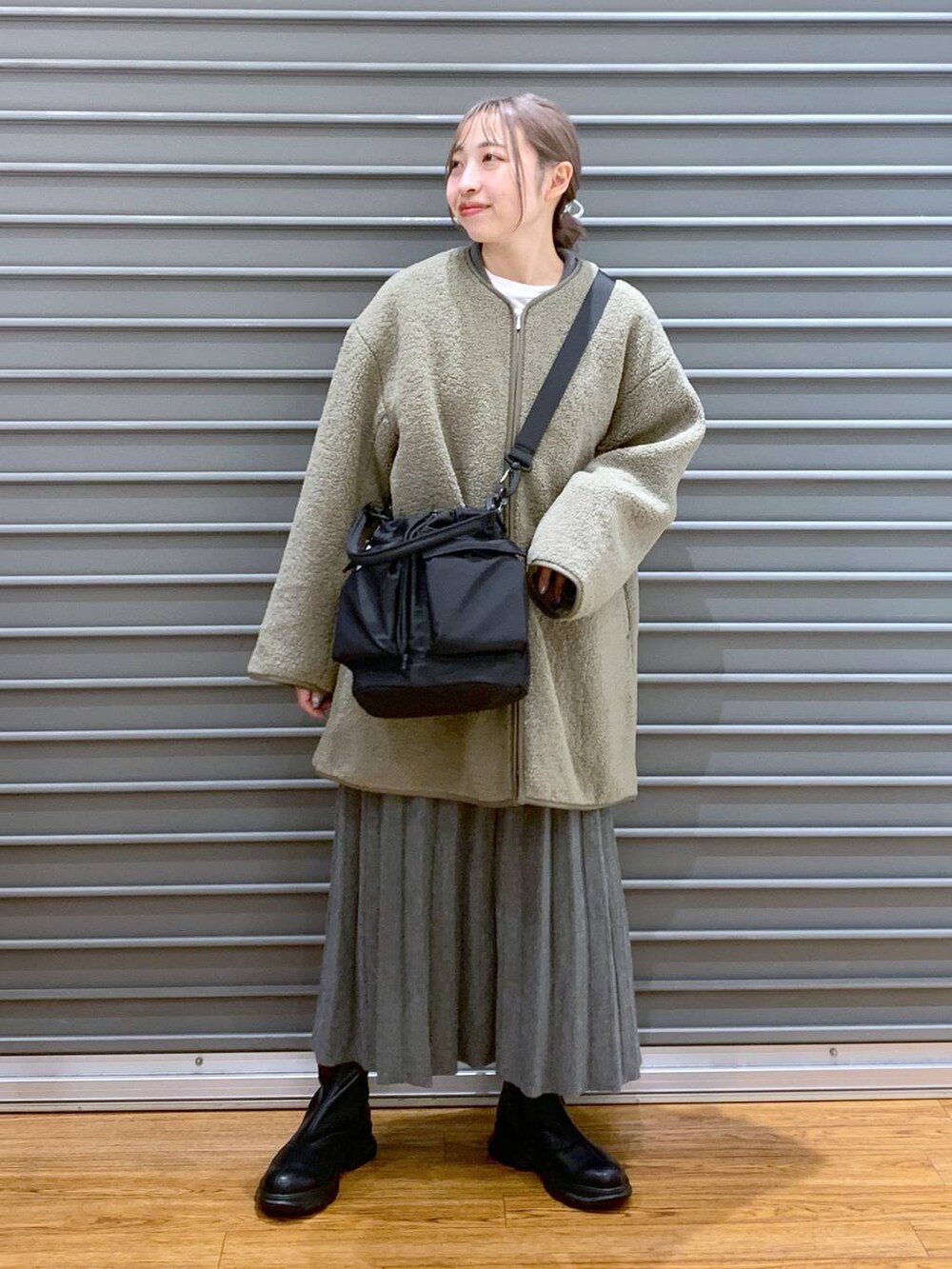 ブラック系のショルダーバッグ、グリーン系のその他アウター、ブラック系のブーツを着用したレディースの冬コーディネートの8枚目の写真