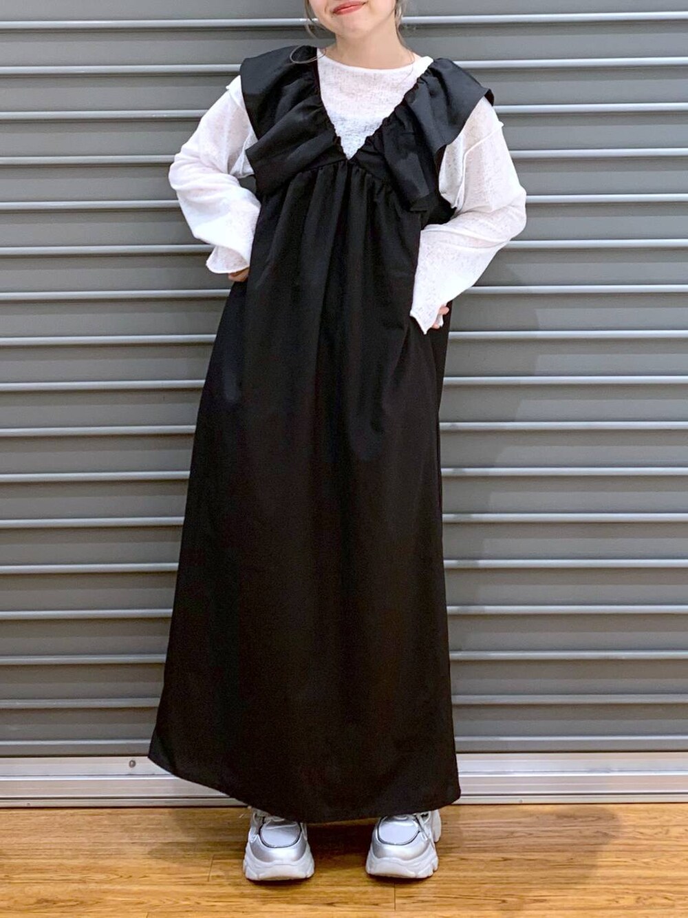 ブラック系のジャンパースカート、シルバー系のスニーカー、ホワイト系のTシャツ/カットソーを着用したレディースの春コーディネートの7枚目の写真