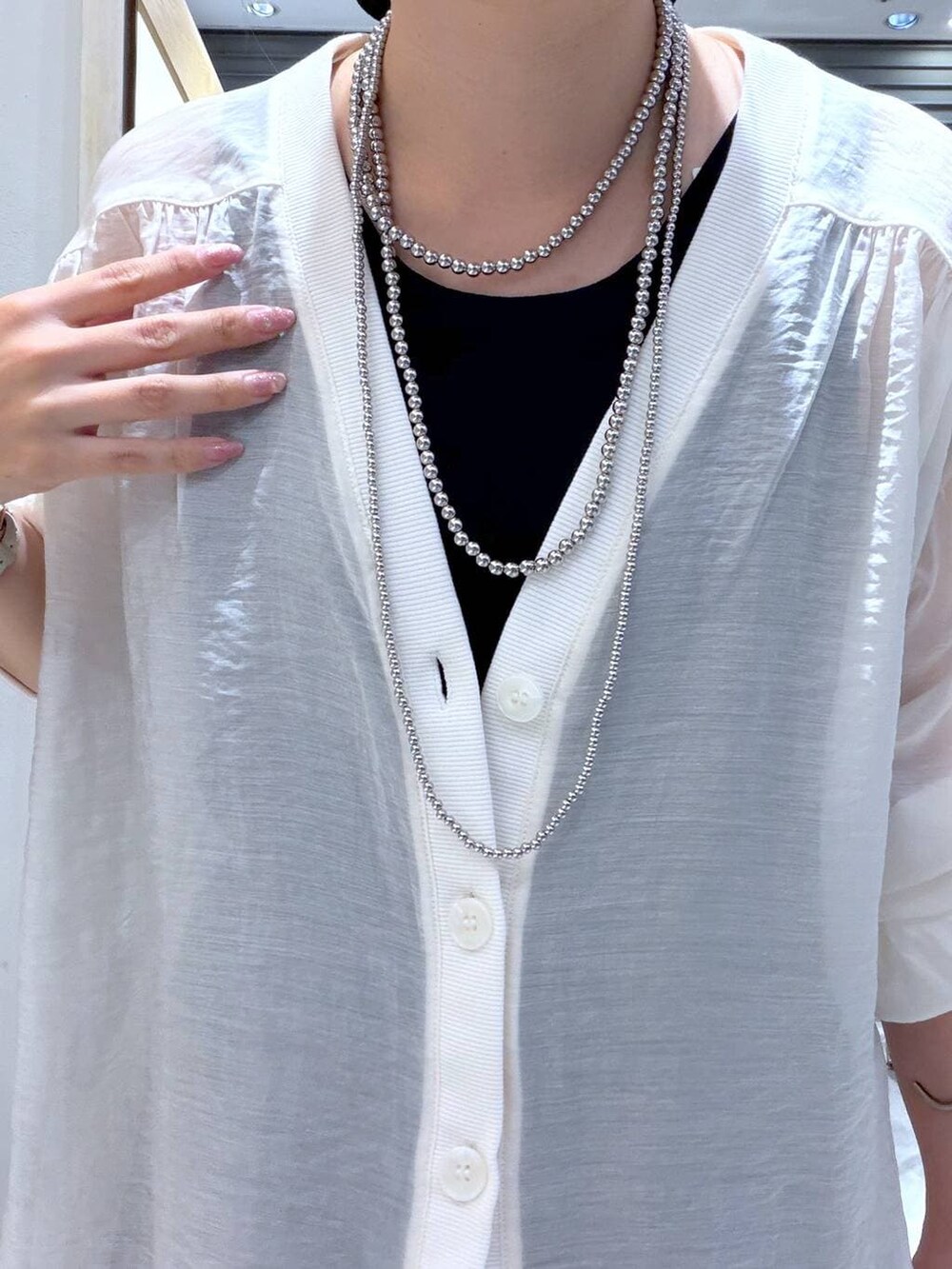 ベージュ系のシャツ/ブラウス、ブラック系のスカート、ブラック系のパンプスを着用したレディースの春コーディネートの4枚目の写真