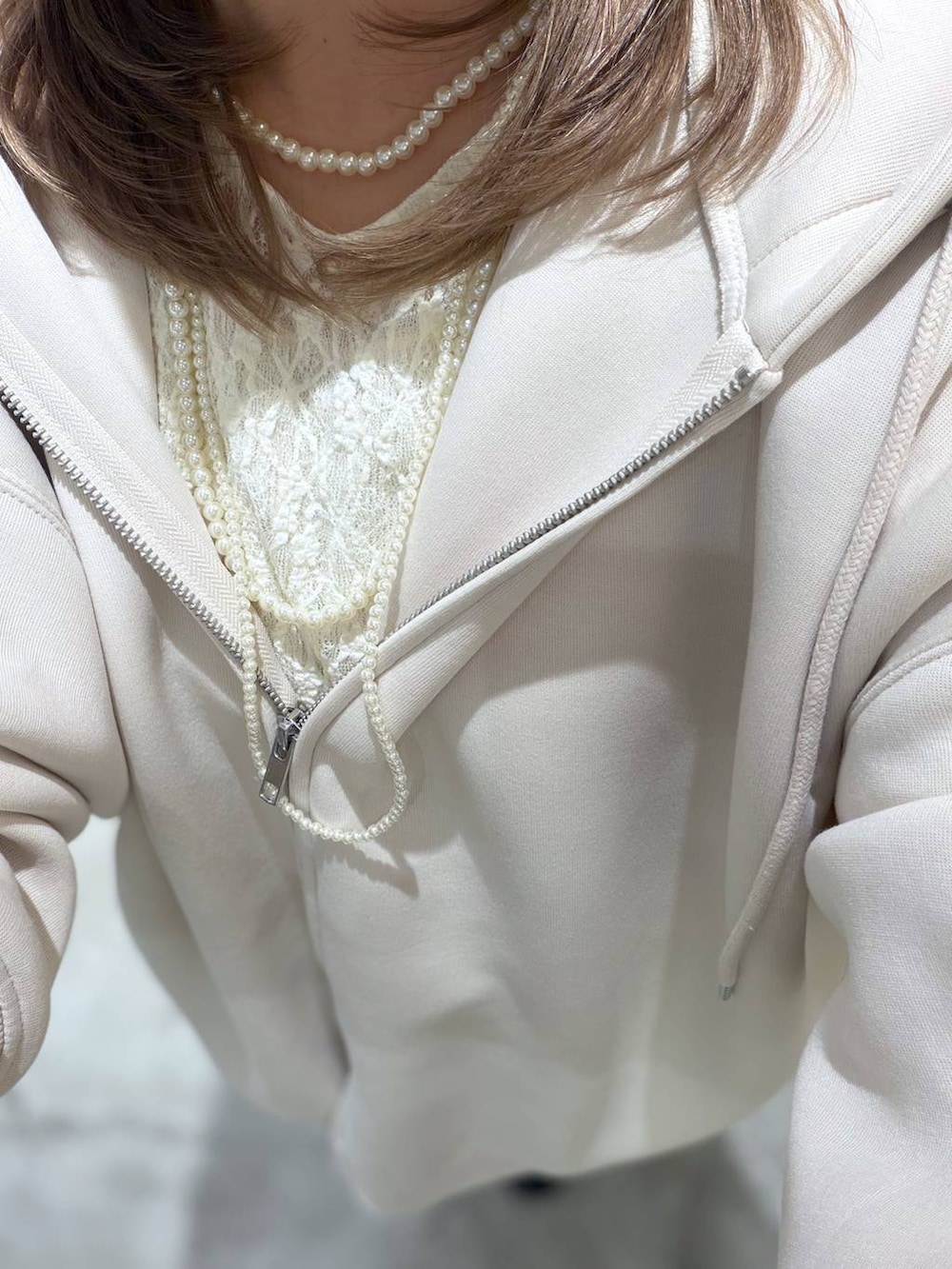 ホワイト系のパーカー、ブルー系のデニムパンツ、ホワイト系のTシャツ/カットソーを着用したレディースの春コーディネートの6枚目の写真