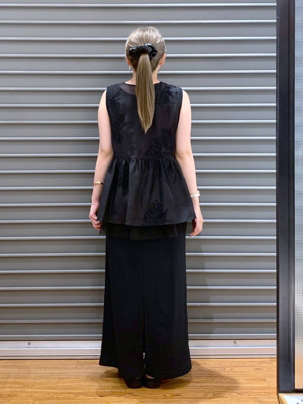 ホワイト系のサンダル、ホワイト系のハンドバッグ、ブラック系のシャツ/ブラウスを着用したレディースの夏コーディネートの2枚目の写真