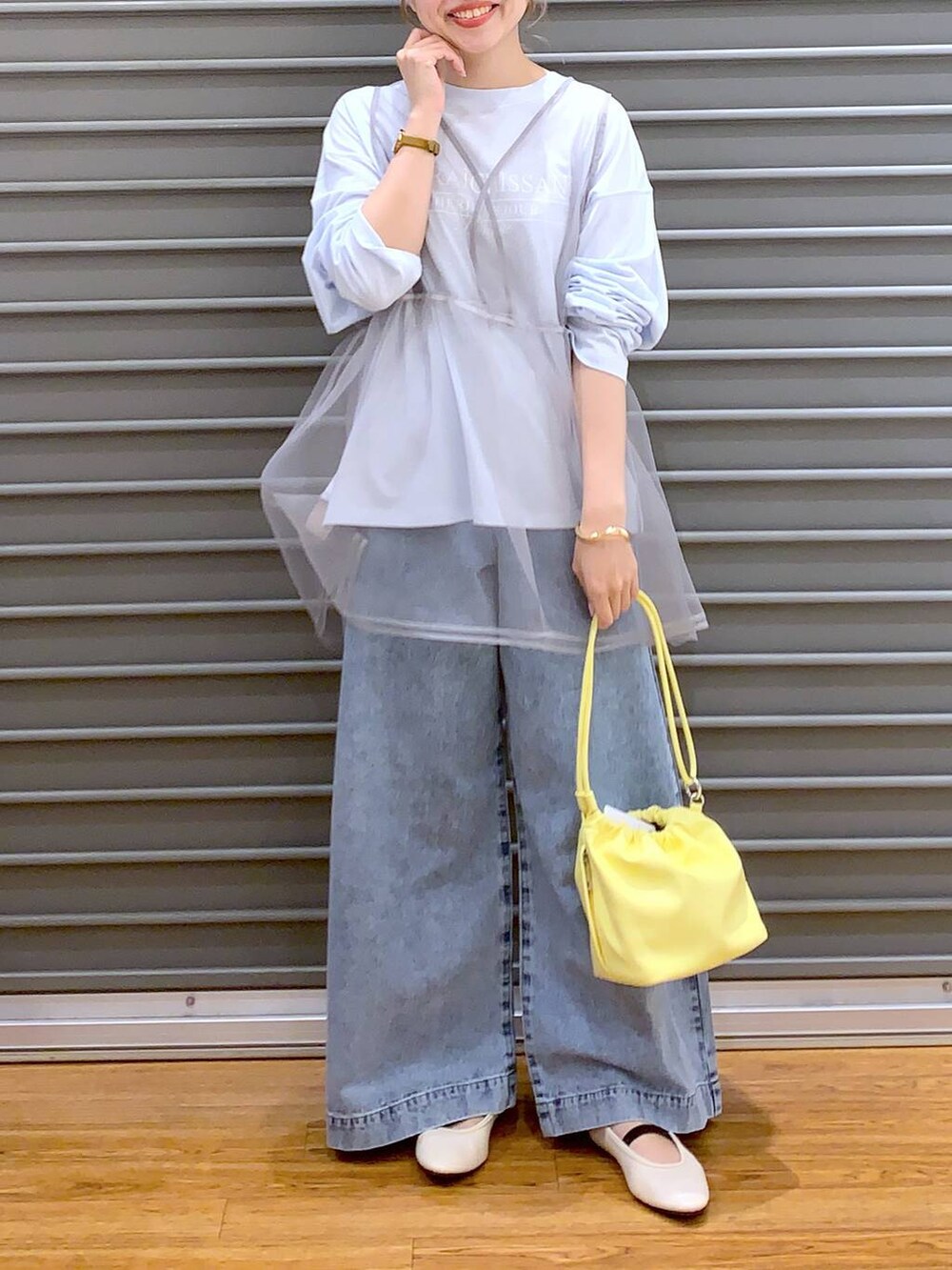 ブルー系のデニムパンツ、ホワイト系のバレエシューズ、イエロー系のショルダーバッグを着用したレディースの春コーディネートの6枚目の写真