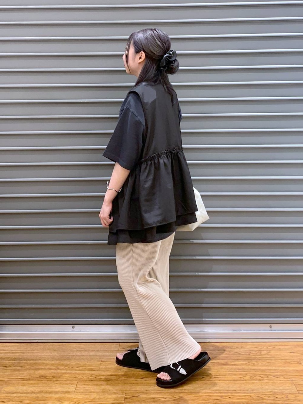 ブラック系のベスト、ベージュ系のその他パンツ、ブラック系のサンダルを着用したレディースの夏コーディネートの3枚目の写真