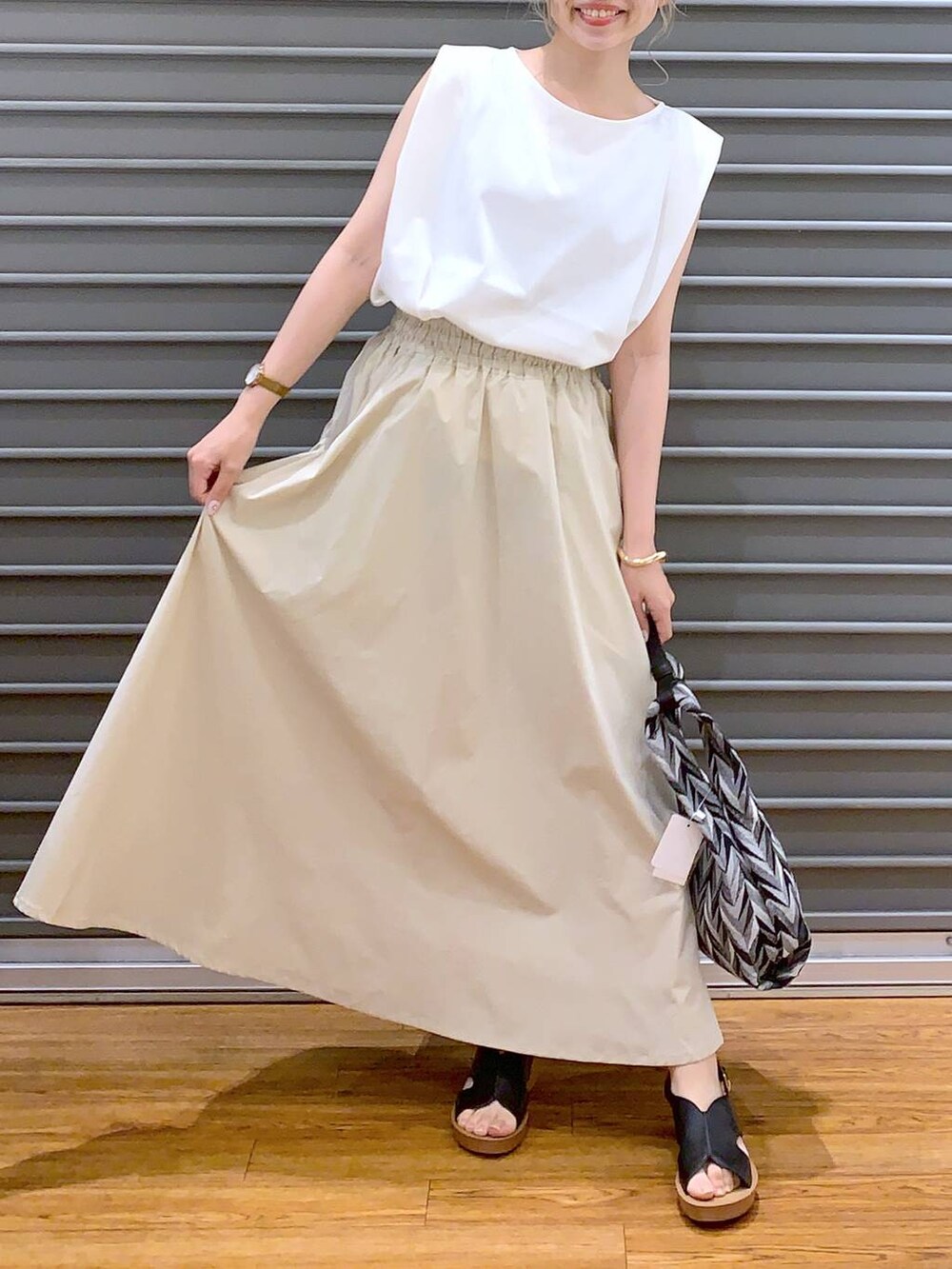 ブラック系のハンドバッグ、ホワイト系のスカート、ブラック系のサンダルを着用したレディースの夏コーディネートの5枚目の写真