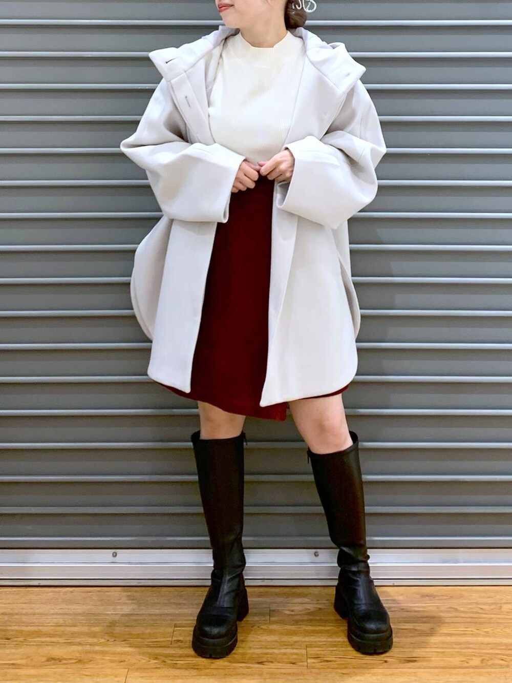 ホワイト系のポンチョ、ホワイト系のニット/セーター、ブラック系のブーツを着用したレディースの冬コーディネートの6枚目の写真