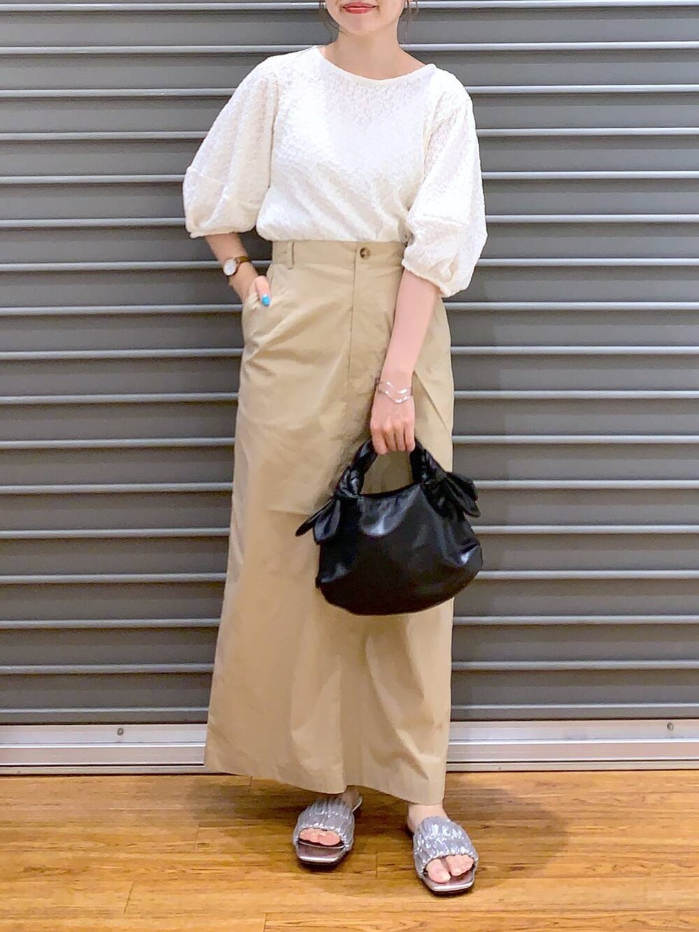 ホワイト系のTシャツ/カットソー、ベージュ系のスカート、ブラック系のショルダーバッグを着用したレディースの夏コーディネートの3枚目の写真