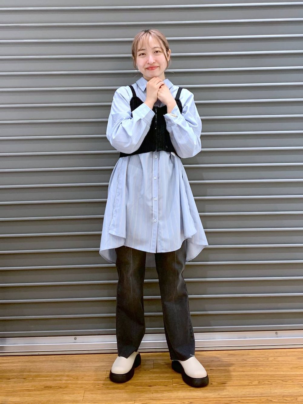 ブラック系のニット/セーター、ブルー系のチュニック、ホワイト系のトートバッグを着用したレディースの春コーディネートの3枚目の写真