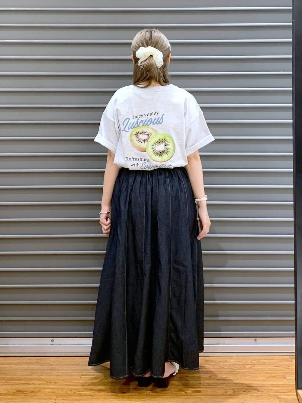 ブルー系のスカート、ホワイト系のサンダル、ブラック系のショルダーバッグを着用したレディースの夏コーディネートの2枚目の写真