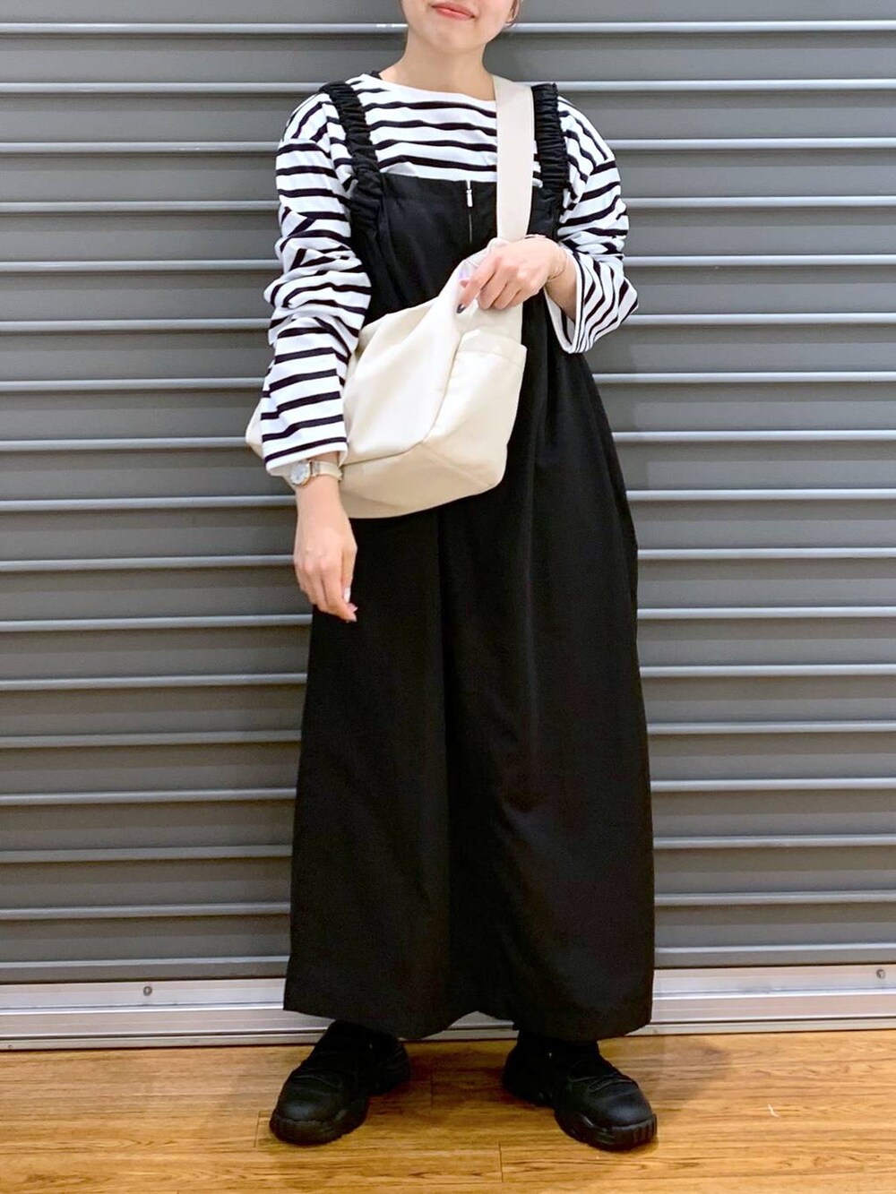 ブルー系のTシャツ/カットソー、ブラック系のスニーカー、ブラック系のジャンパースカートを着用したレディースの冬コーディネートの4枚目の写真
