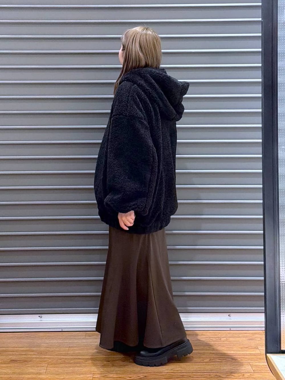 ブラック系のブーツ、ブラウン系のスカート、ブラック系のボストンバッグを着用したレディースの冬コーディネートの3枚目の写真