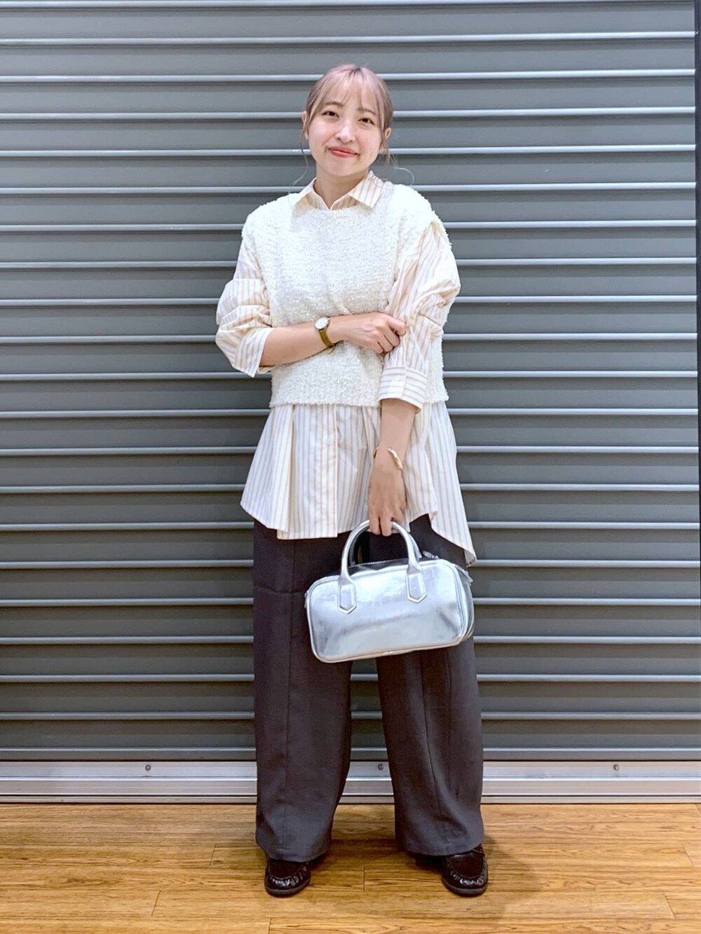 シルバー系のボストンバッグ、ホワイト系のベスト、オレンジ系のシャツ/ブラウスを着用したレディースの秋コーディネートの3枚目の写真