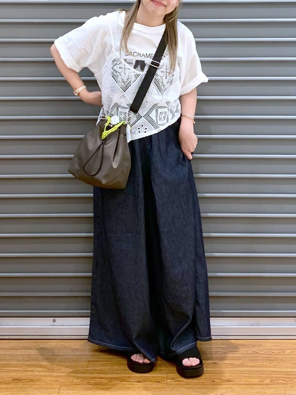 ブラック系のサンダル、ブルー系のデニムパンツ、ブラウン系のショルダーバッグを着用したレディースの夏コーディネートの5枚目の写真