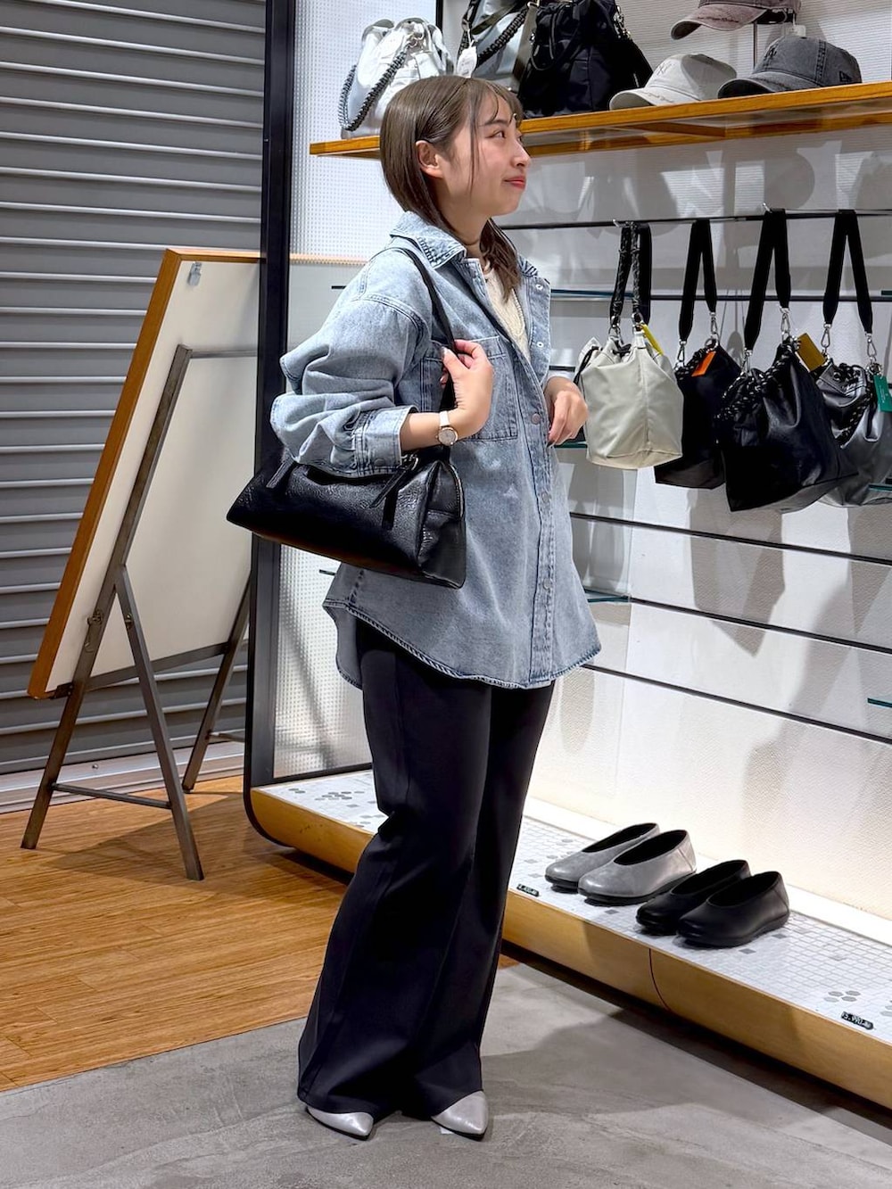 ブラック系のボストンバッグ、シルバー系のパンプス、ブルー系のシャツ/ブラウスを着用したレディースの冬コーディネートの6枚目の写真