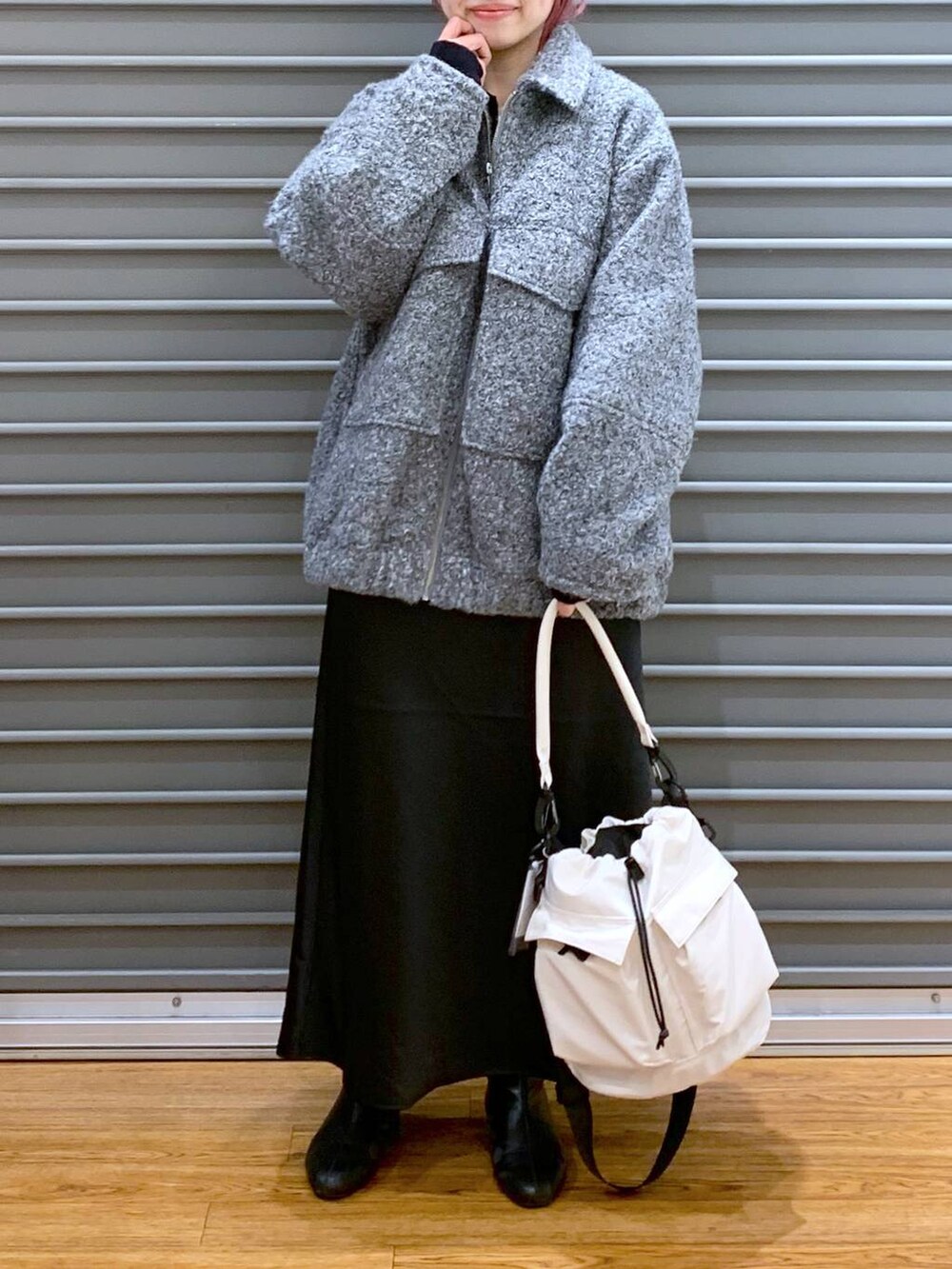 ホワイト系のショルダーバッグ、ブラック系のスカート、ブラック系のブーツを着用したレディースの秋コーディネートの3枚目の写真