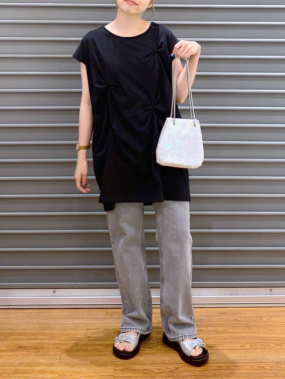 ホワイト系のショルダーバッグ、シルバー系のサンダル、グレー系のデニムパンツを着用したレディースの夏コーディネートの5枚目の写真