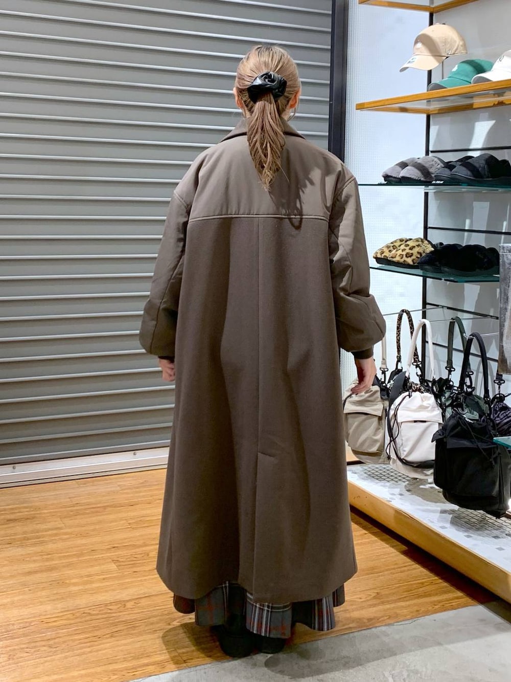 ブラック系のブーツ、グレー系のスカート、ブラック系のショルダーバッグを着用したレディースの冬コーディネートの2枚目の写真